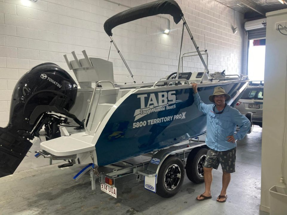 Man Stands Proudly Next to a New Teal and White Boat on a Trailer — In Tune Marine in Cairns, QLD