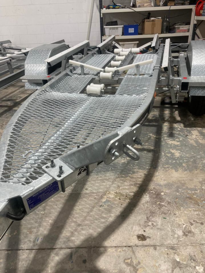 A Metal Boat Trailer With Rollers And A Winch Attachment Sits In A Workshop — In Tune Marine in Mackay, QLD