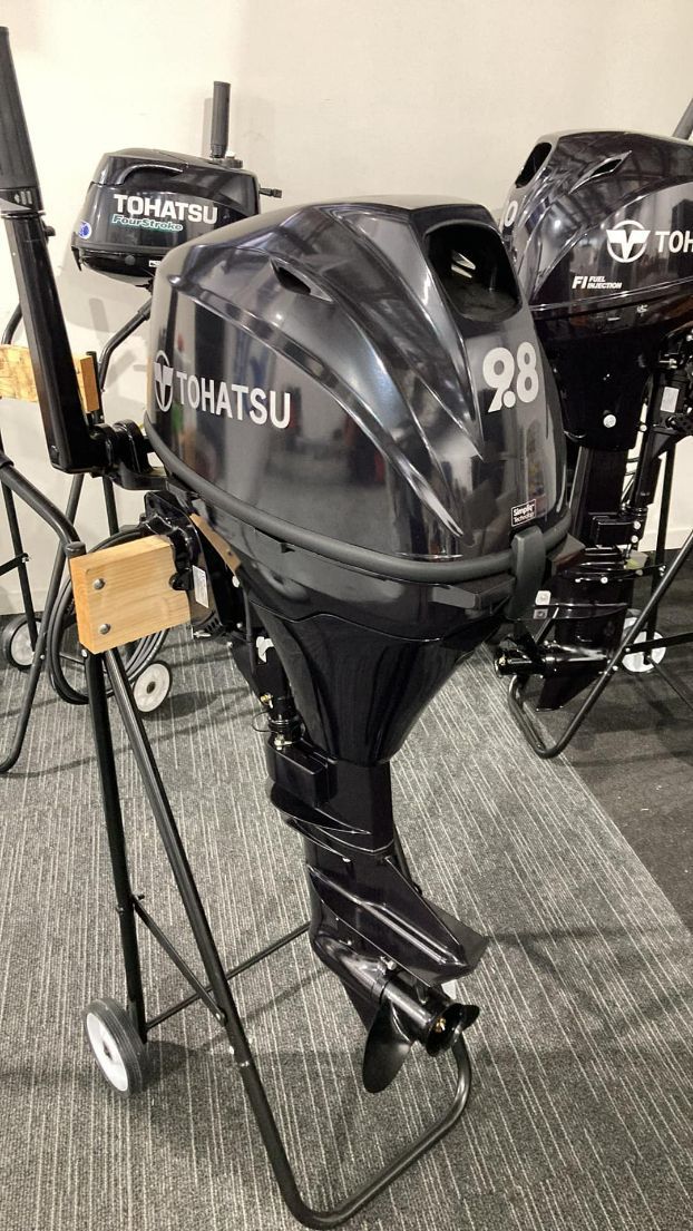 Dark Blue Tohatsu 28 Outboard Motor On A Black Stand. Others Are Blurred In Background — In Tune Marine in Airlie Beach, QLD