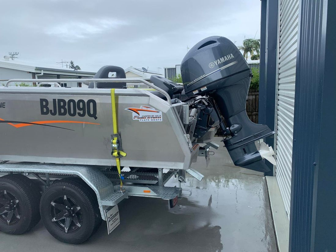 Boat on a Trailer With a Yamaha Motor Leaning Against a Building — In Tune Marine in Airlie Beach, QLD