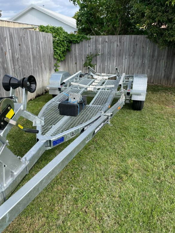 Galvanized Boat Trailer On Grass, Near A Wooden Fence — In Tune Marine in Mackay, QLD