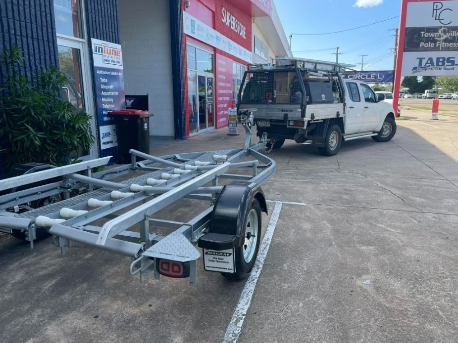 White Truck With A Boat Trailer Parked Outside A Store — In Tune Marine in Mackay, QLD
