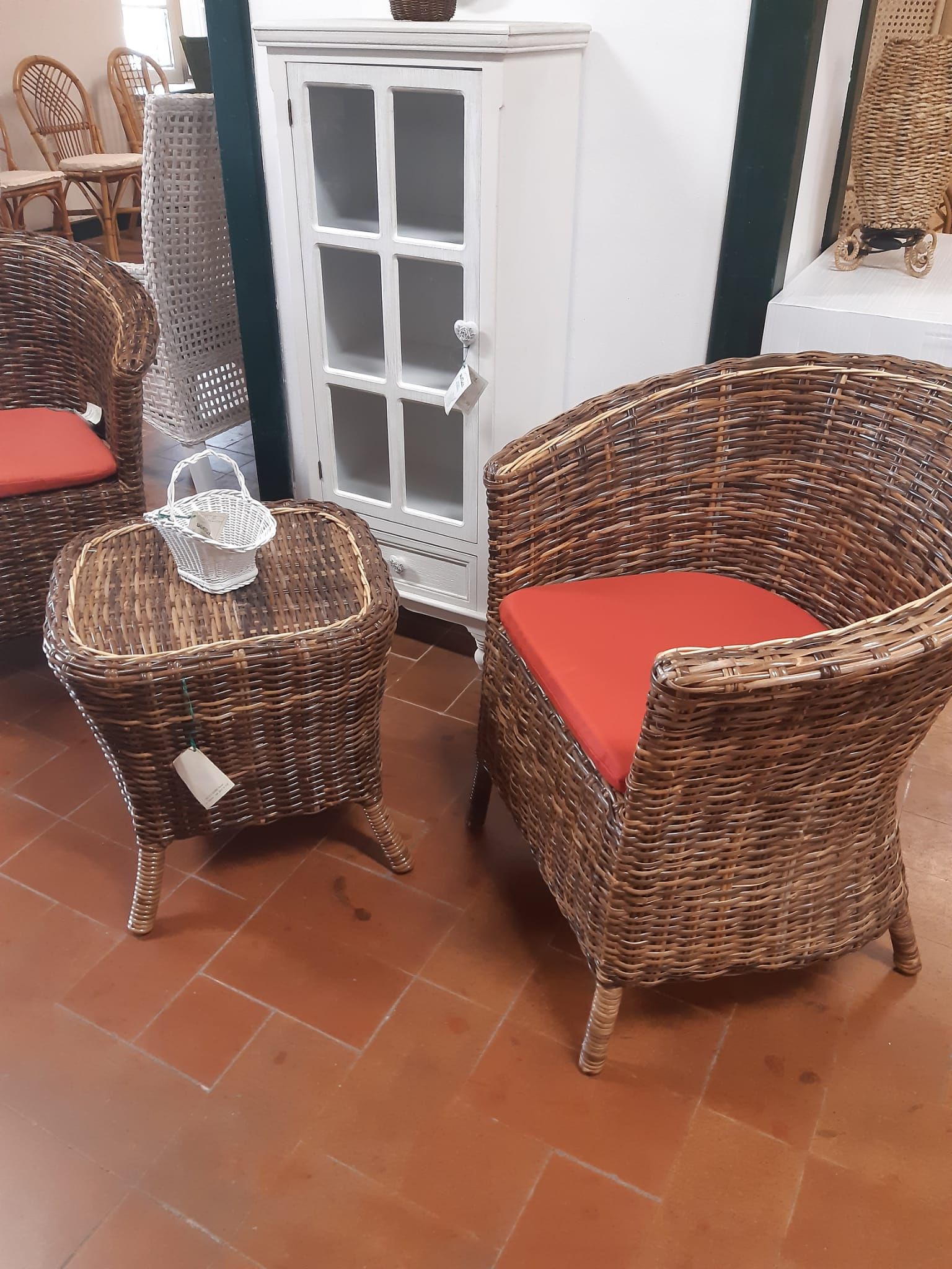 Due sedie di vimini e un tavolo con un cuscino rosso in una stanza.