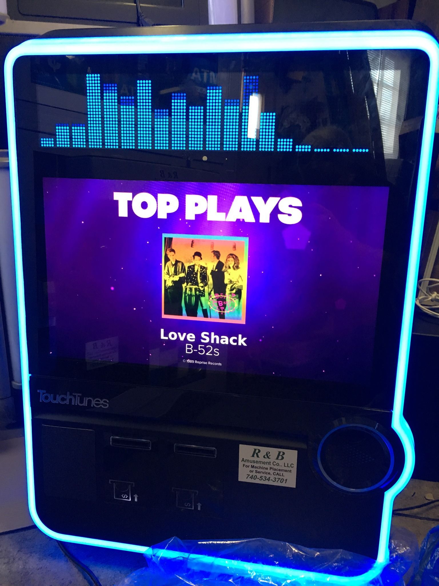 A glowing blue LED jukebox screen displays 