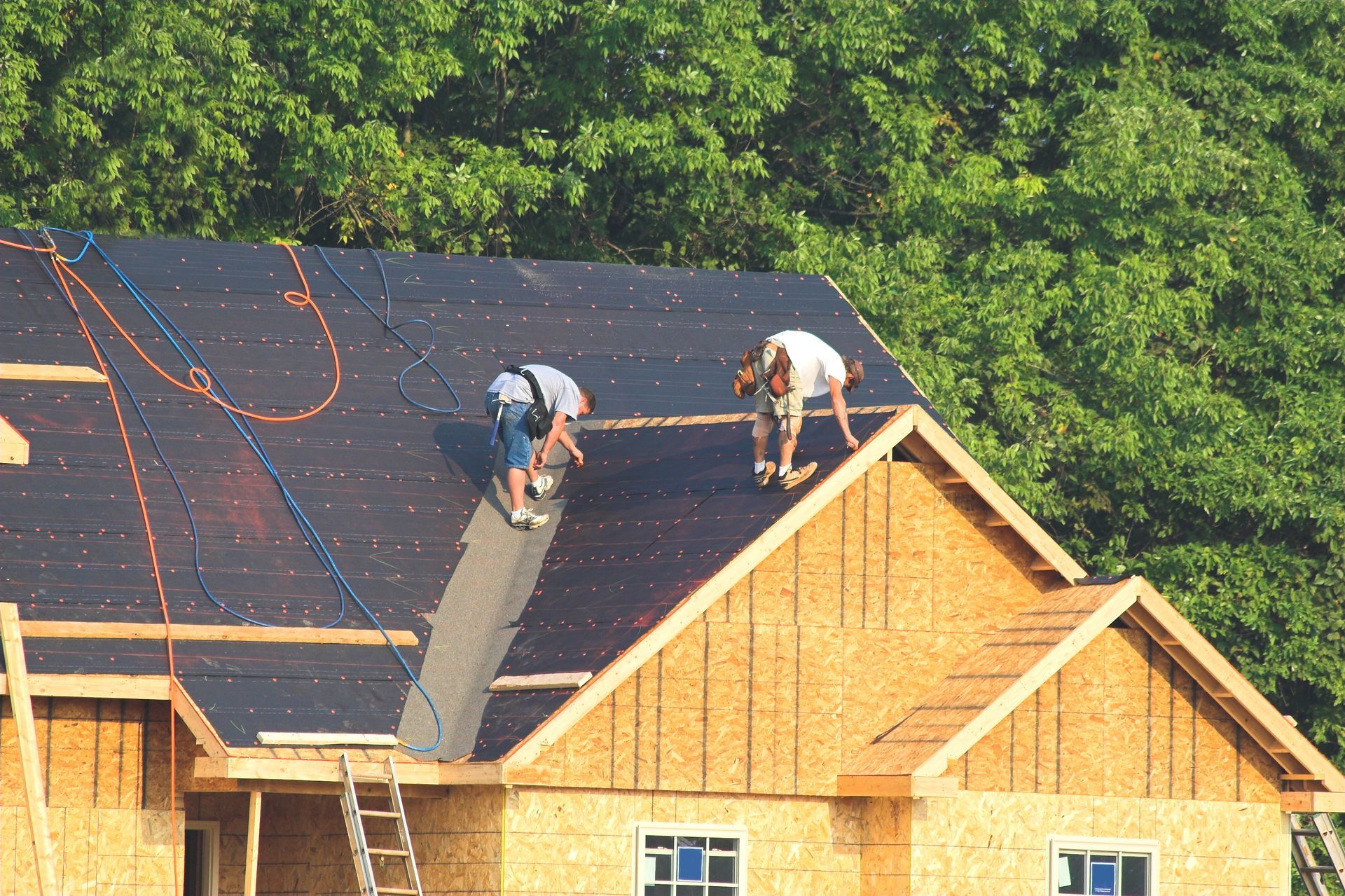 Local roofers are installing protective underlayment on the roof of a new residential construction.