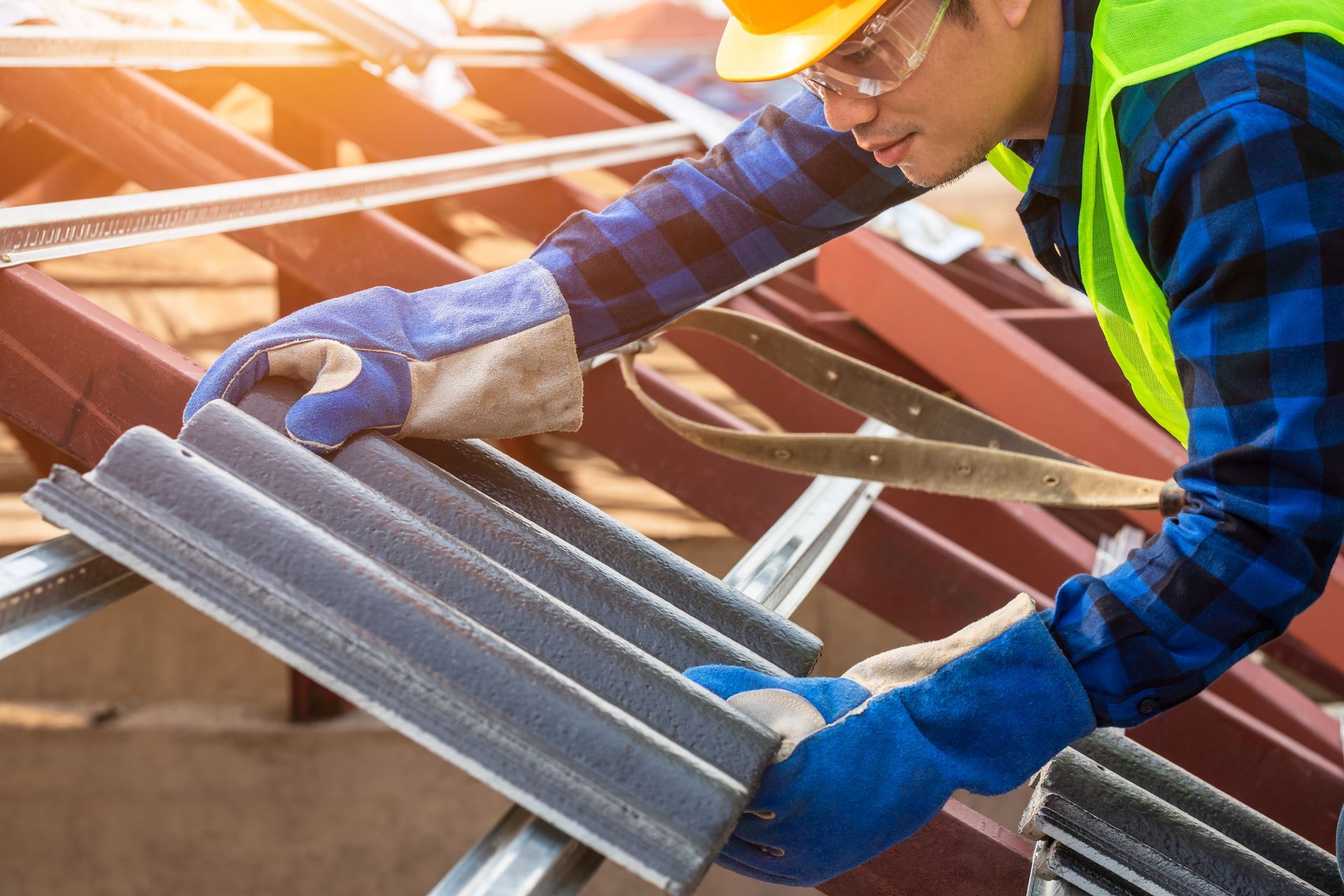 Roofing contractor installing tile panels on a residential roof with protective gloves and gear.