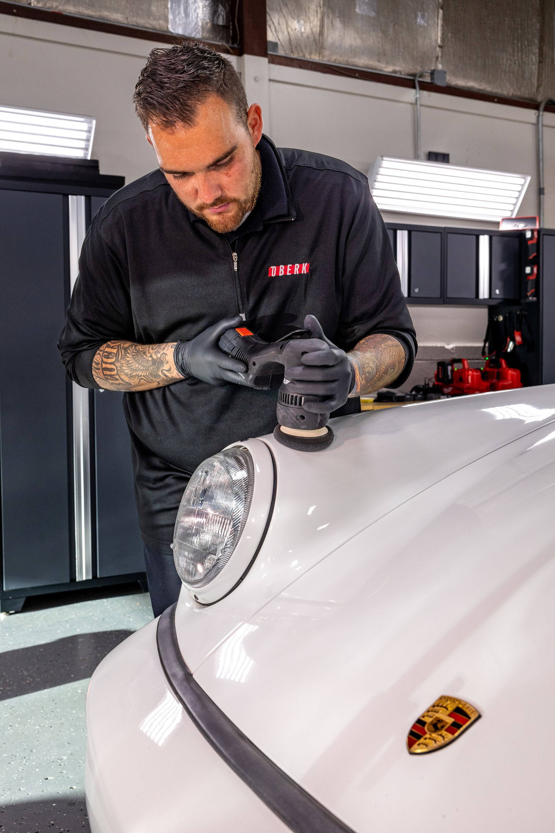 A red sports car is covered in foam in a garage.