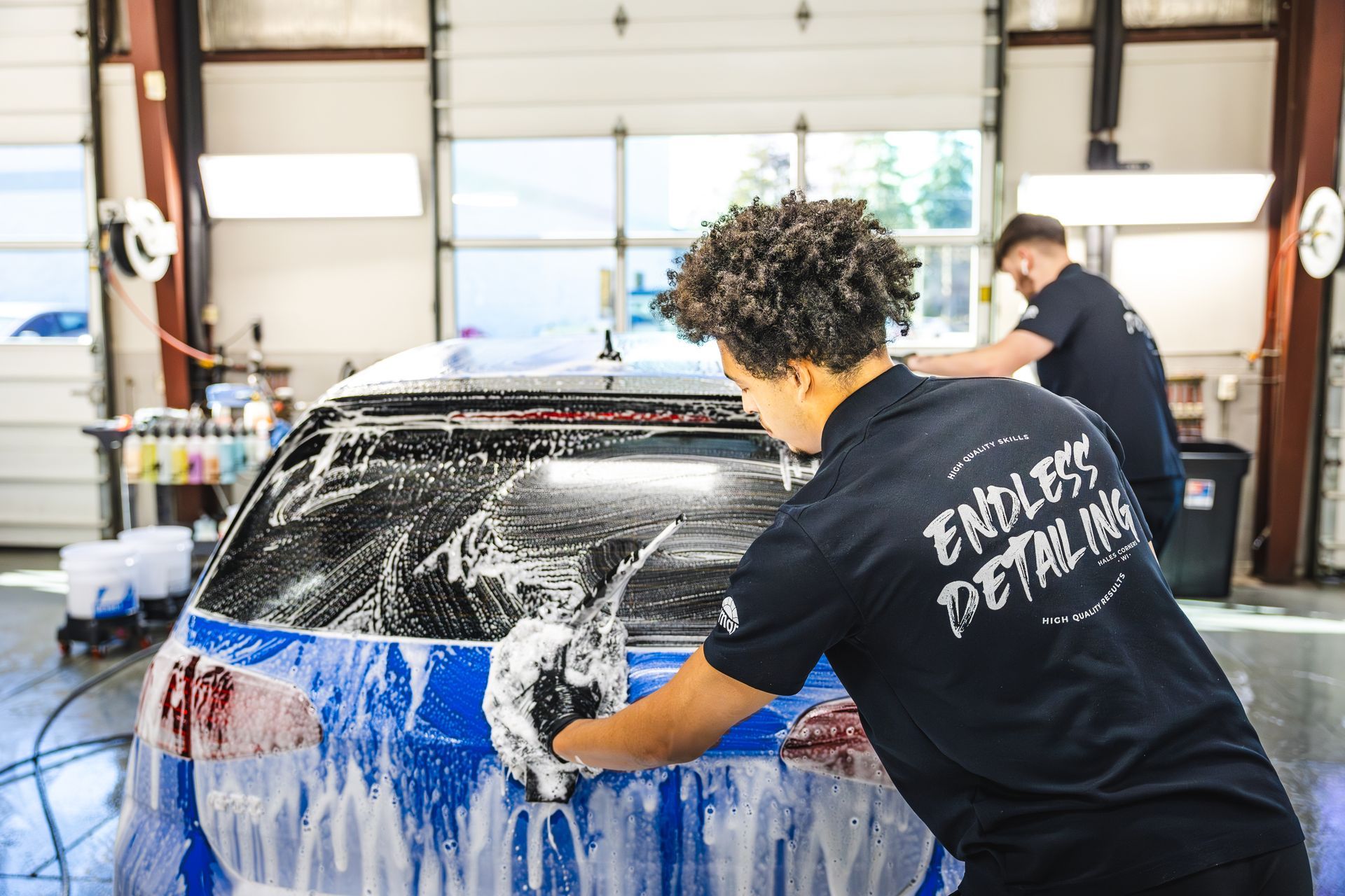A blue car with a spoiler on the back is parked in a garage.