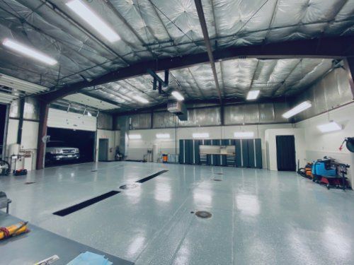 A large empty garage with a car parked in the back.
