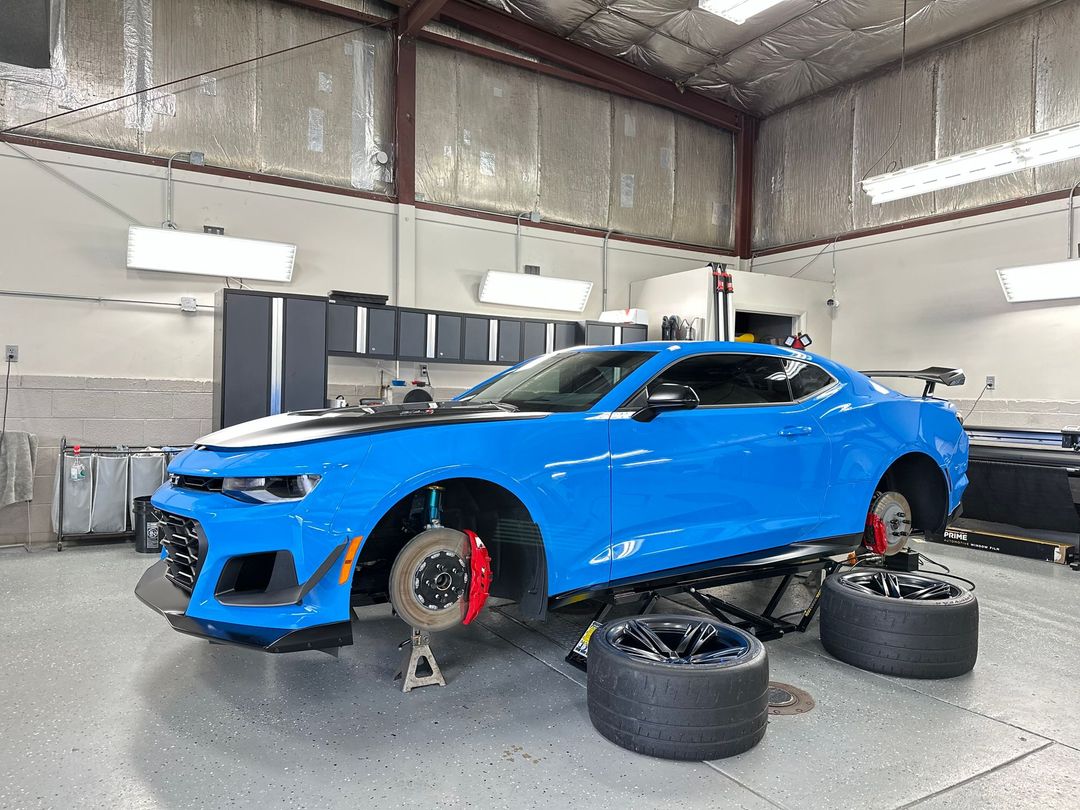 A blue car is sitting on top of a lift in a garage.