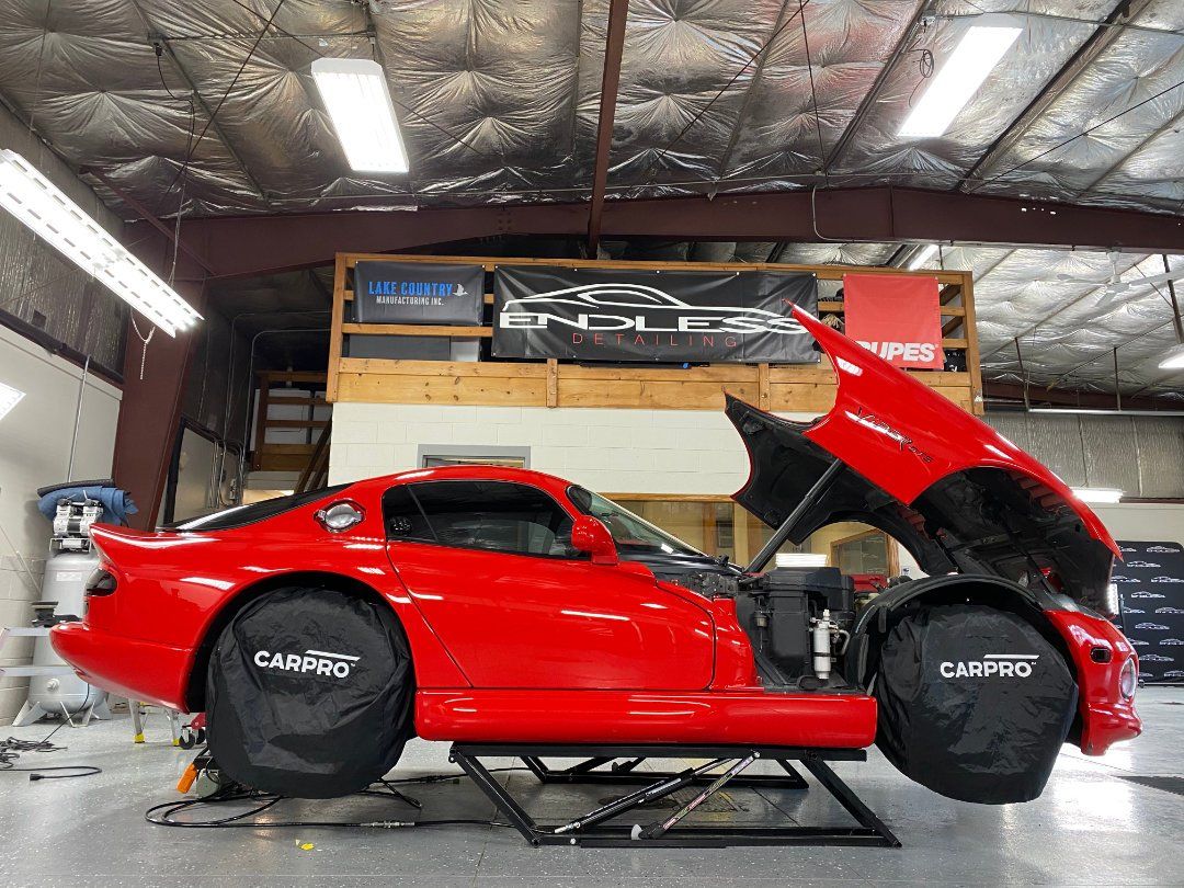 Red Dodge Viper on a lift in a workshop with the hood and door open, wheel covers in place.