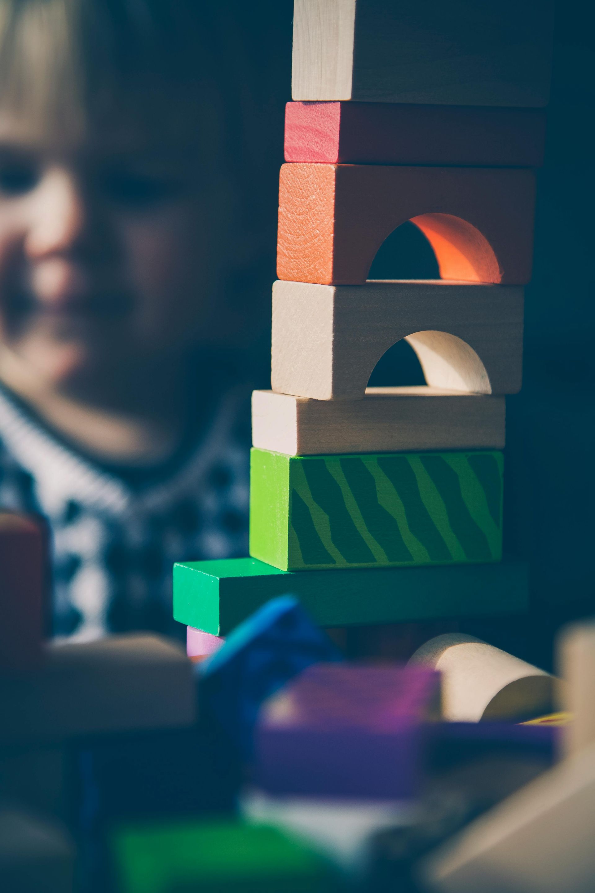 A child is playing with a stack of wooden blocks.