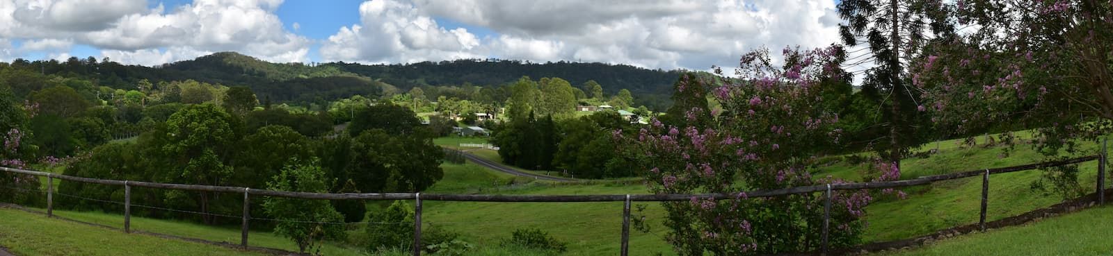A Fence Surrounds A Grassy Field With Trees — JC Hire In Nambour, QLD