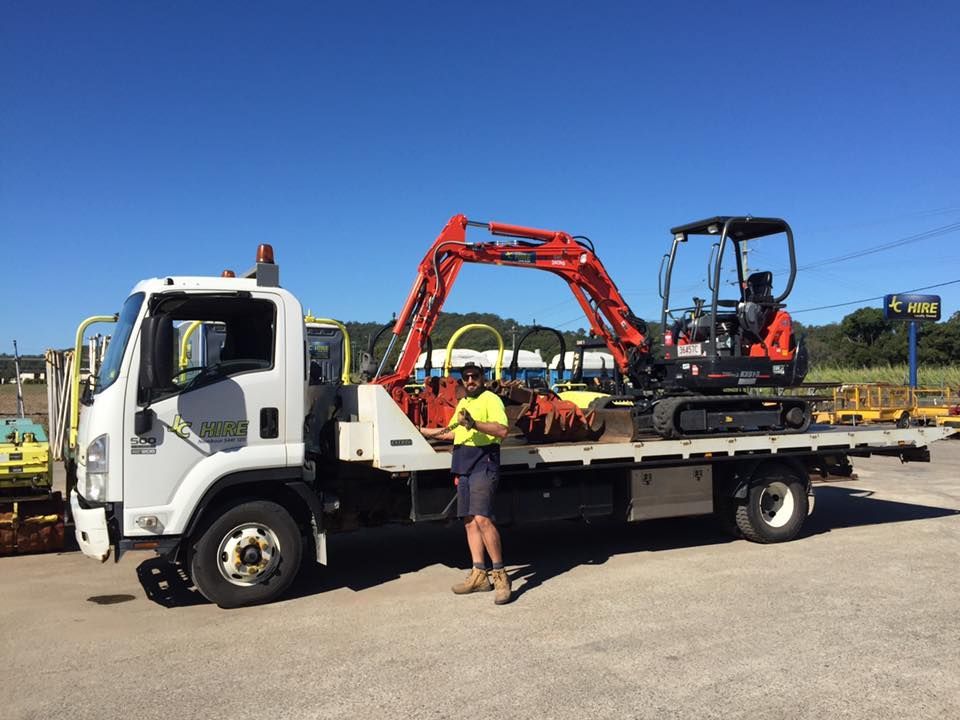 Flatbed Tow Truck Carrying a Red Mini Excavator — JC Hire In Bli Bli, QLD