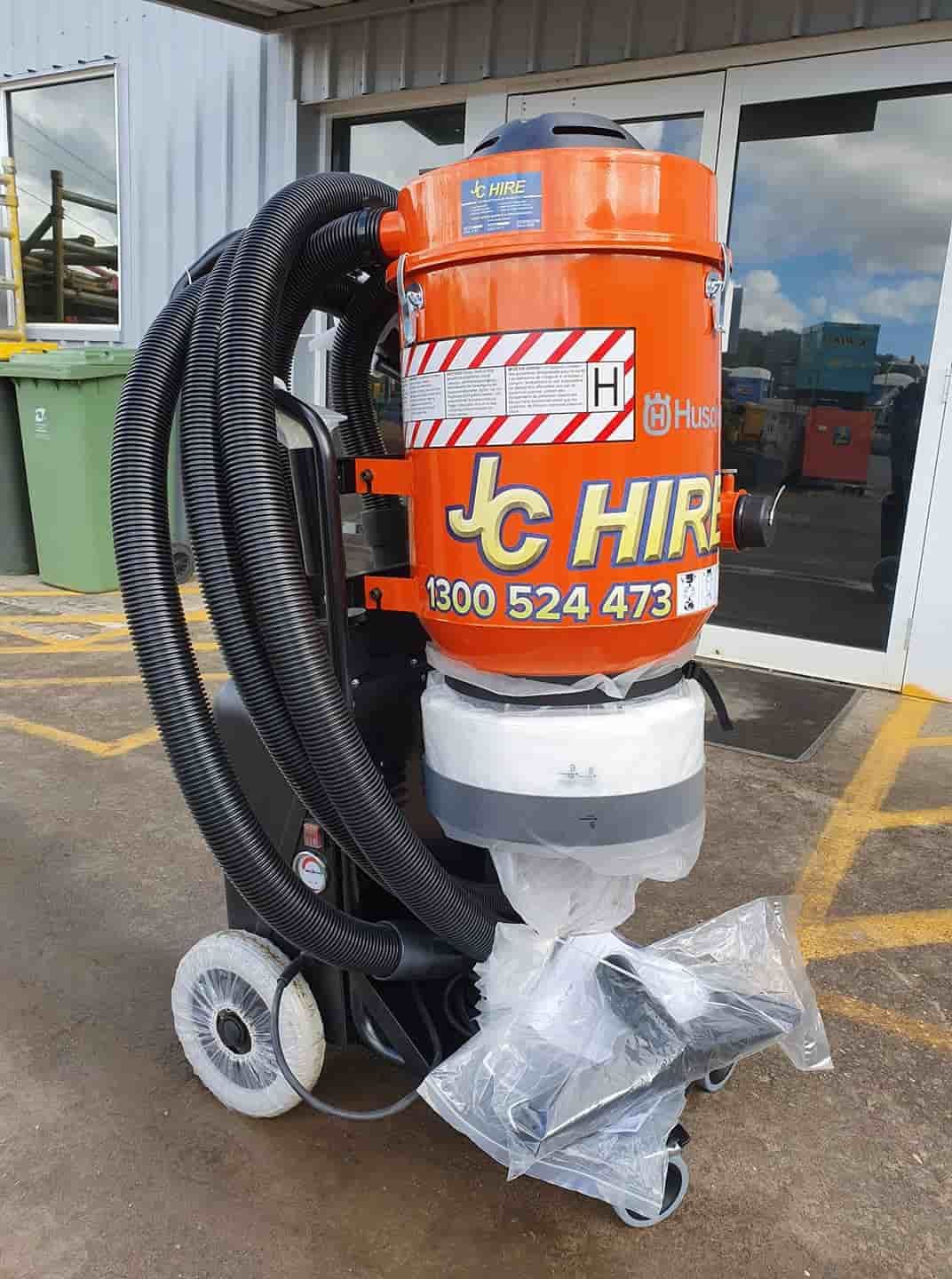 A Vacuum Cleaner Is Sitting In A Parking Lot In Front Of A Building — JC Hire In Bli Bli, QLD