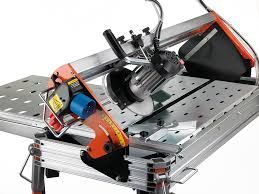 Orange and silver tile saw on a stand, cutting tile.