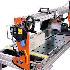 Wet tile saw, orange and silver, on folding legs. Blade spinning, water supply visible, ready for cutting.