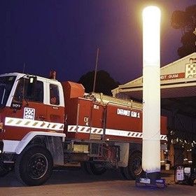 Snowboarder performing a jump at night, lit by a GoPro branded tower, surrounded by a crowd and snow piles.
