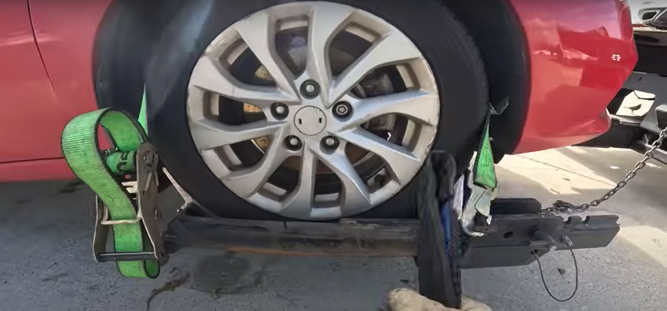 Towing service image of trained operator attaching strop during vehicle recovery.