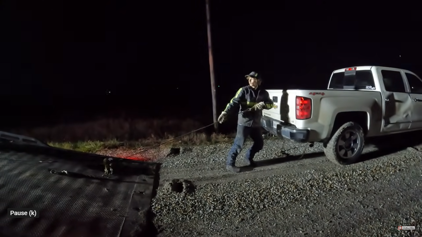 Trained tow truck operator attaching wicnh cable to stranded vehicle