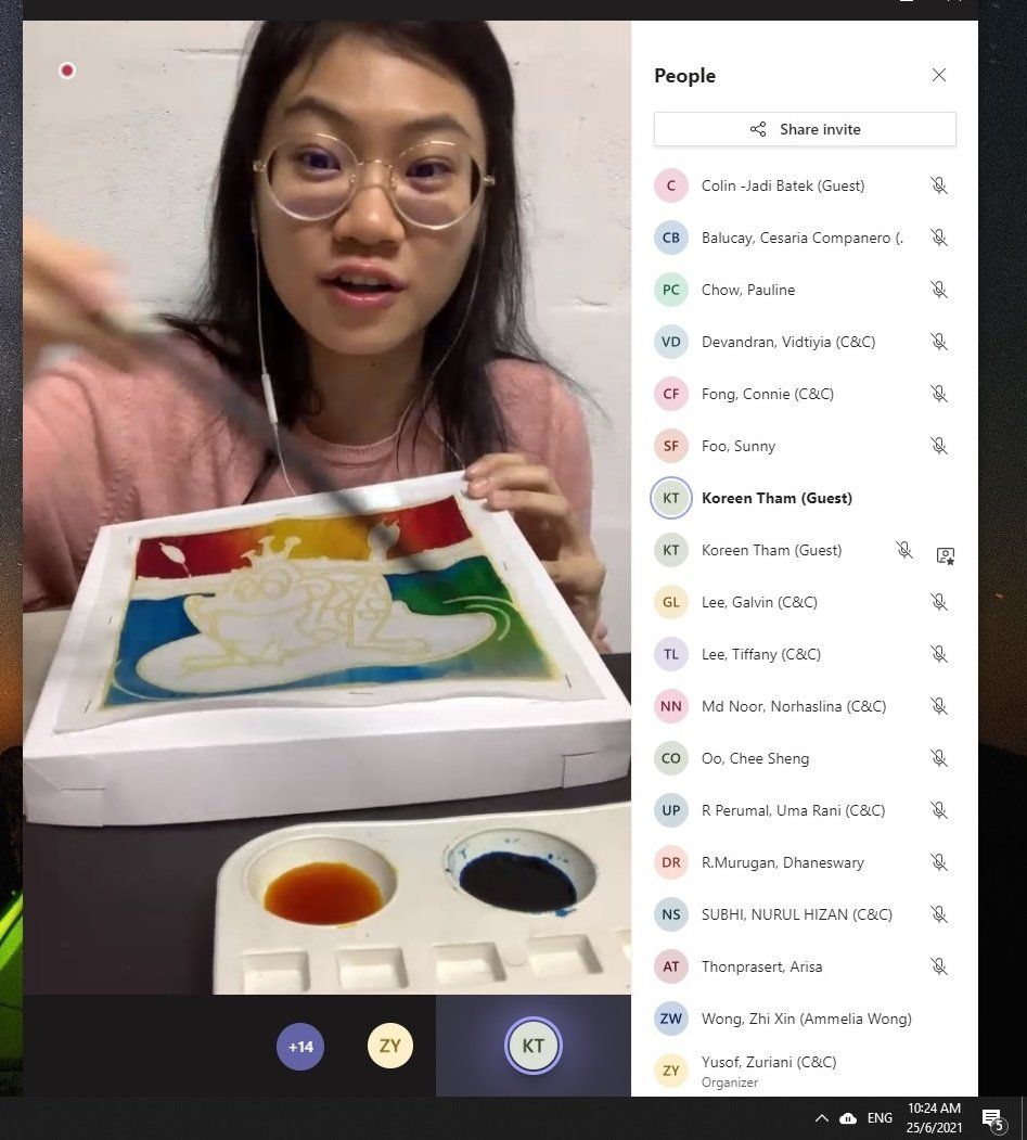 Woman in glasses leading online art class, holding a painting with colorful background.