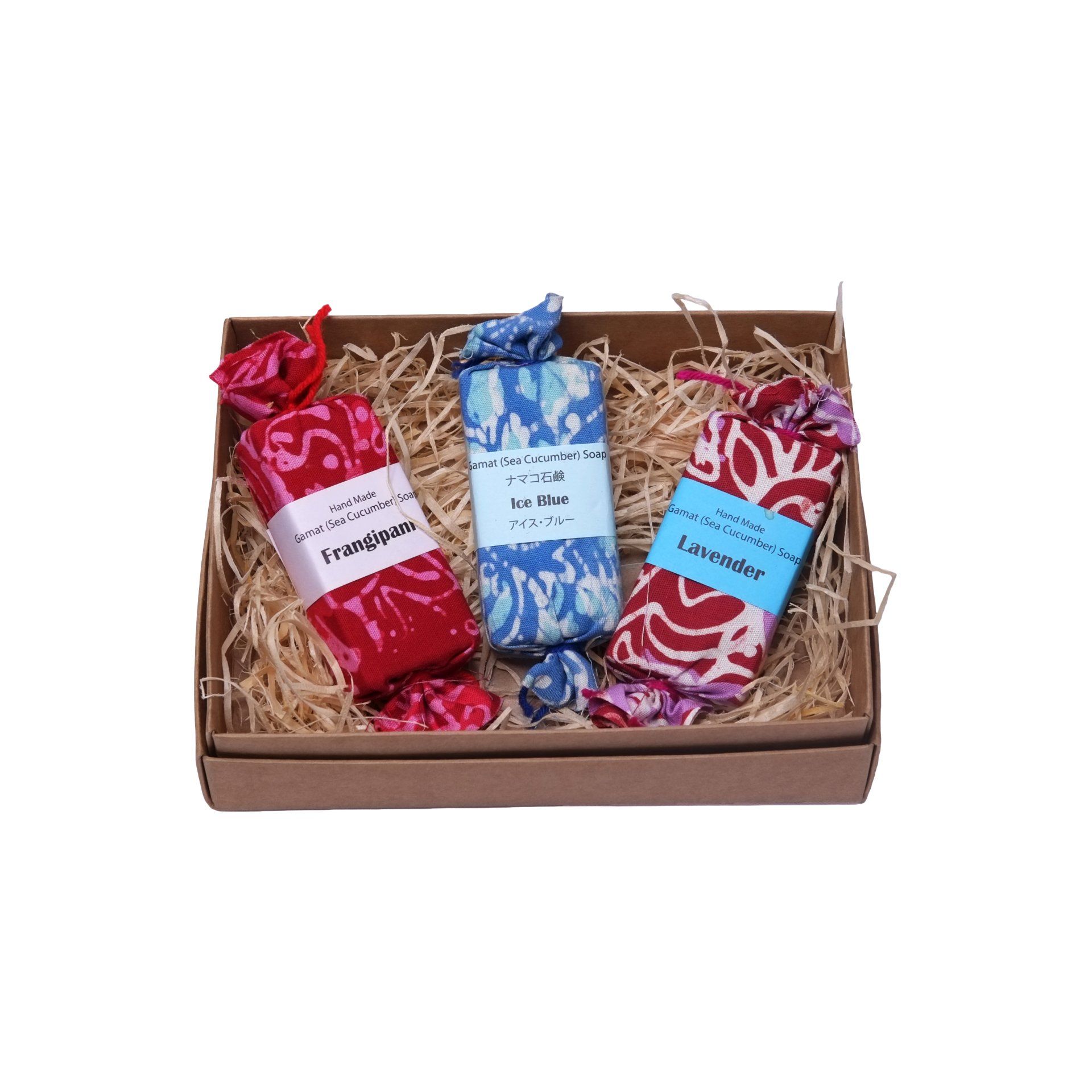 Gift box with three wrapped soaps, red, blue, and patterned, on straw.