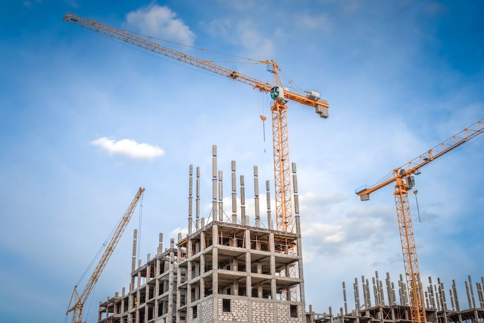 A building is being built with cranes and a blue sky in the background.