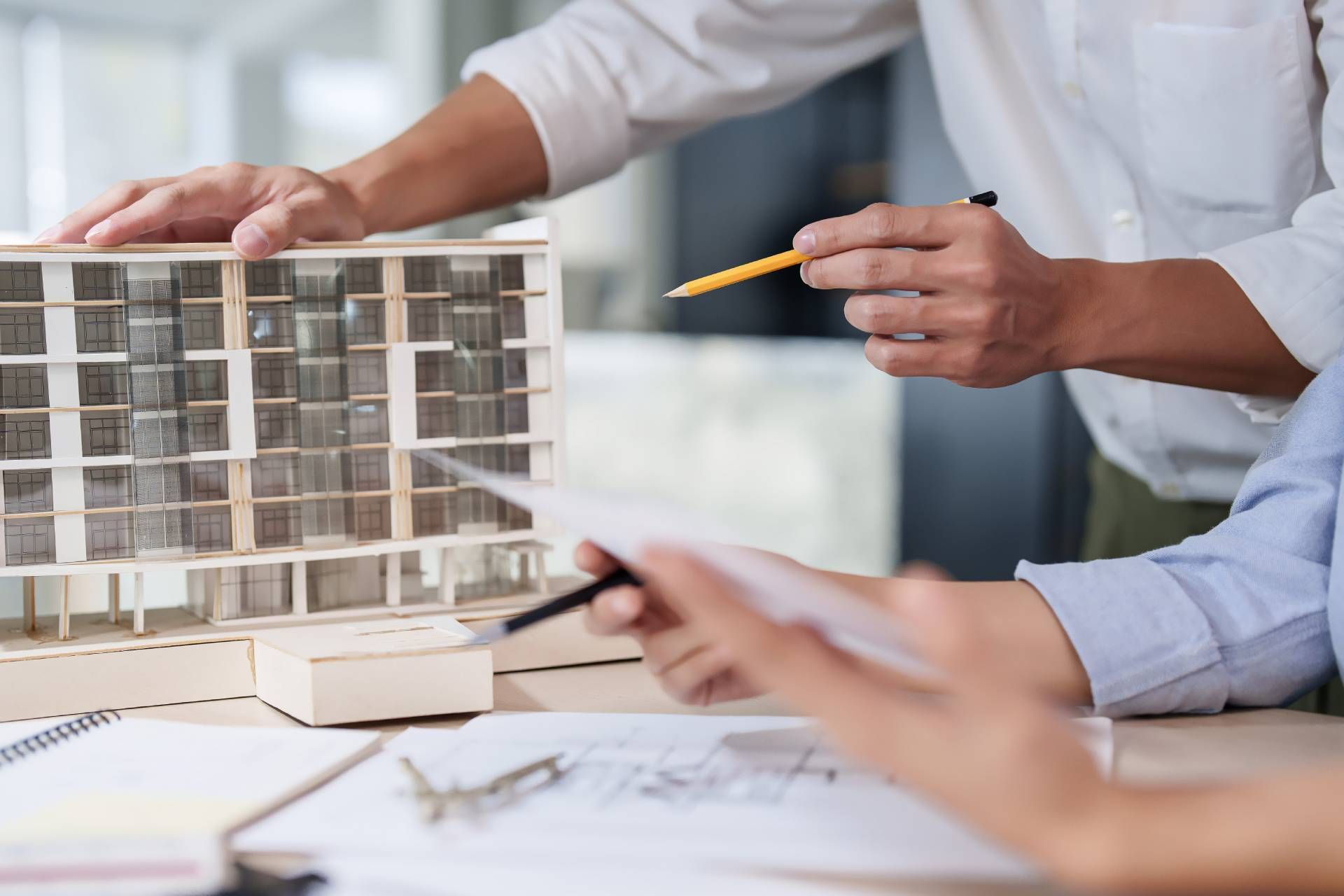 A group of people are sitting at a table looking at a model of a building.