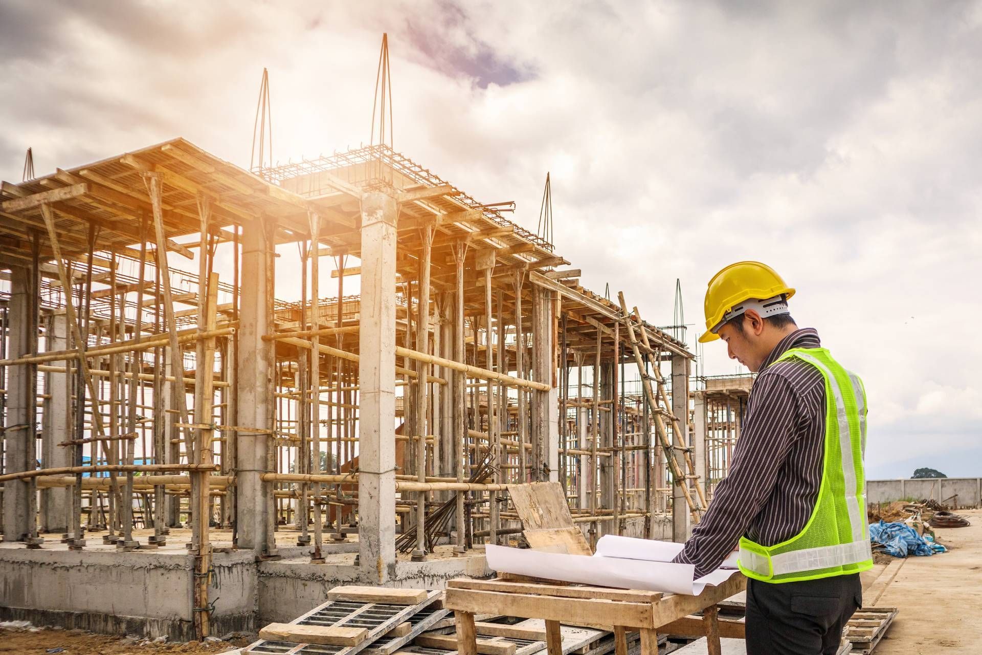 A construction worker is looking at a blueprint at a construction site.