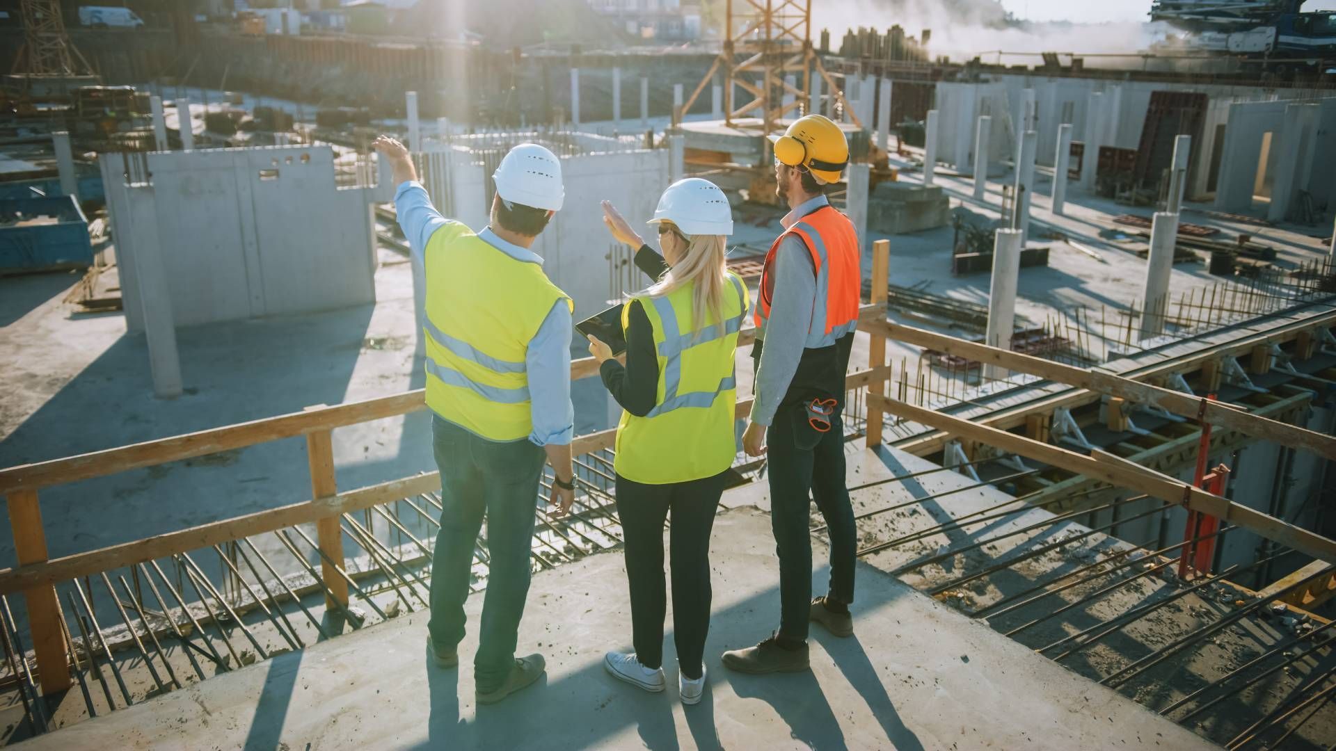A group of construction workers are standing on top of a building under construction.