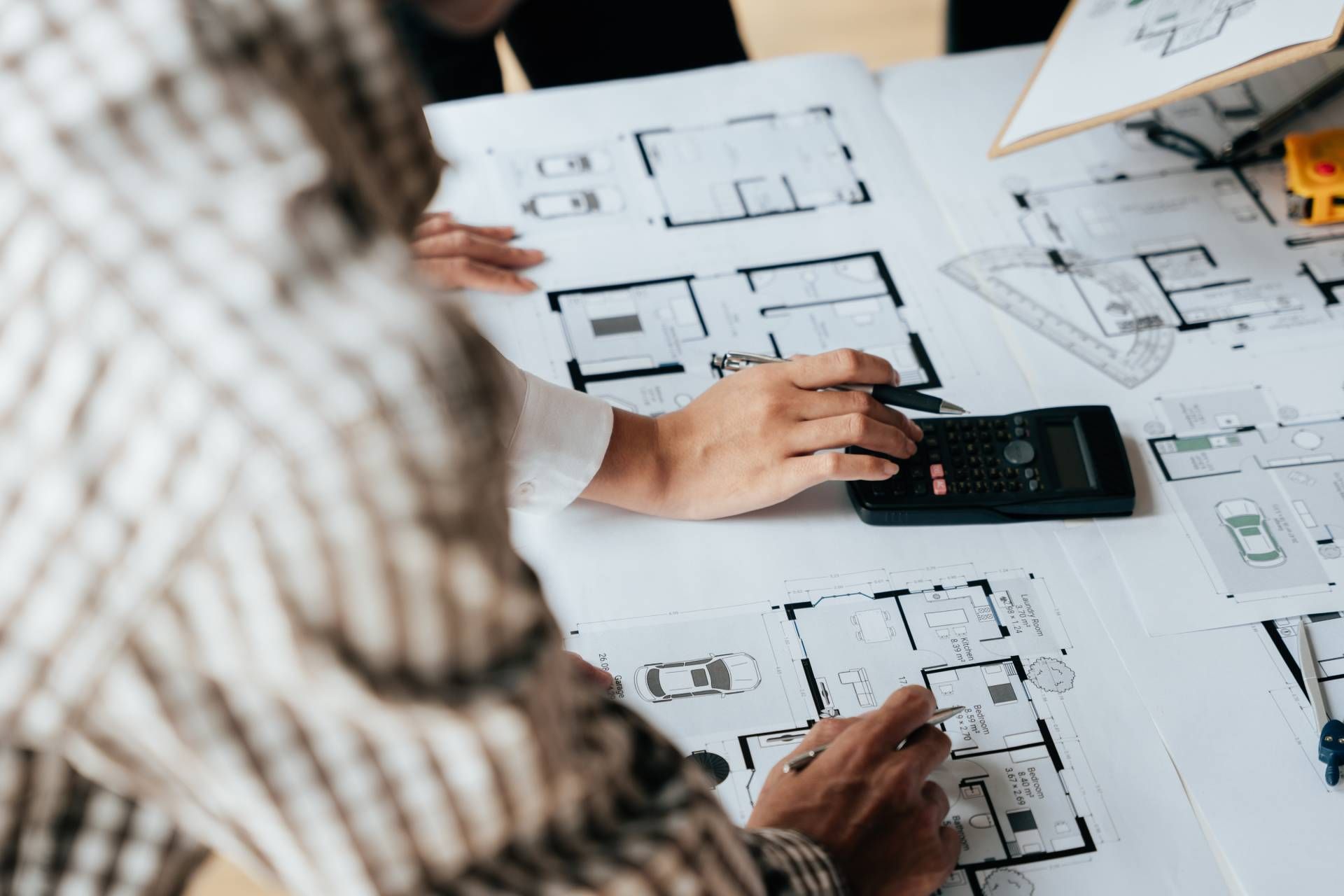 A group of people are sitting at a table looking at floor plans and using a calculator.