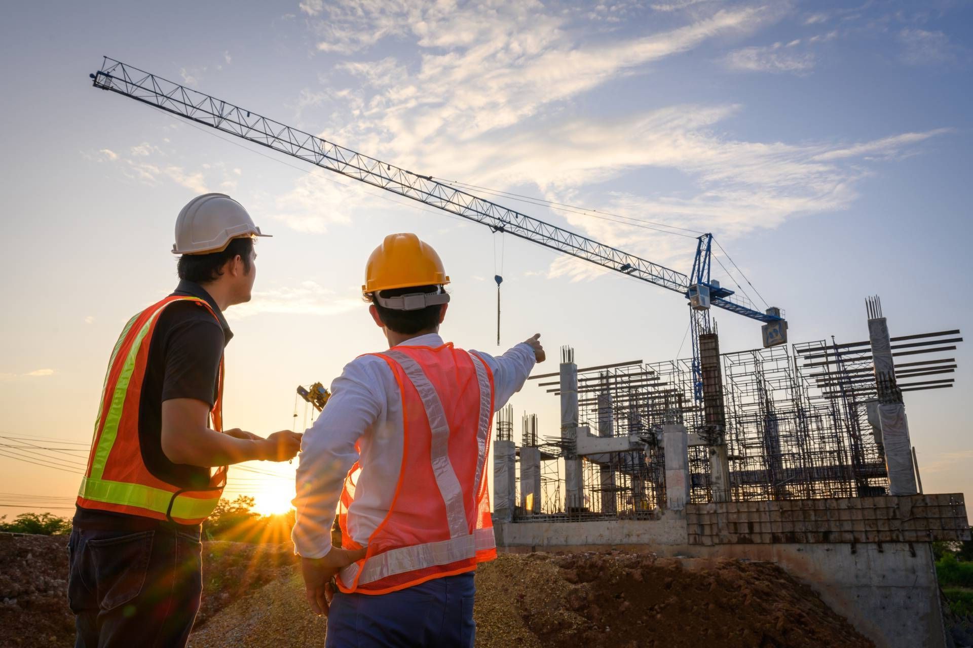 Two construction workers are looking at a building under construction.