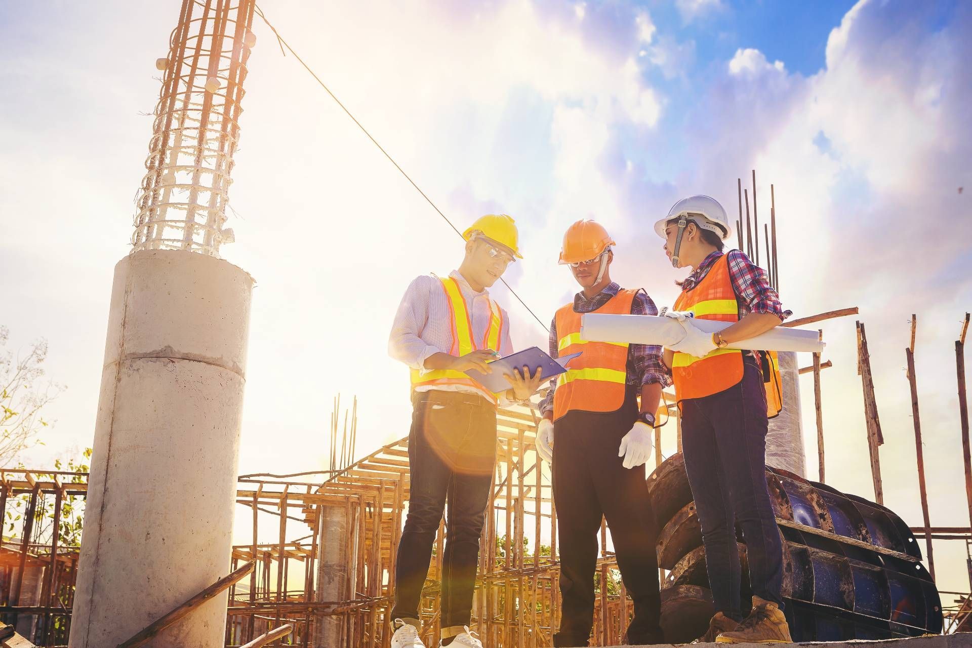A group of construction workers are standing at a construction site looking at a blueprint.