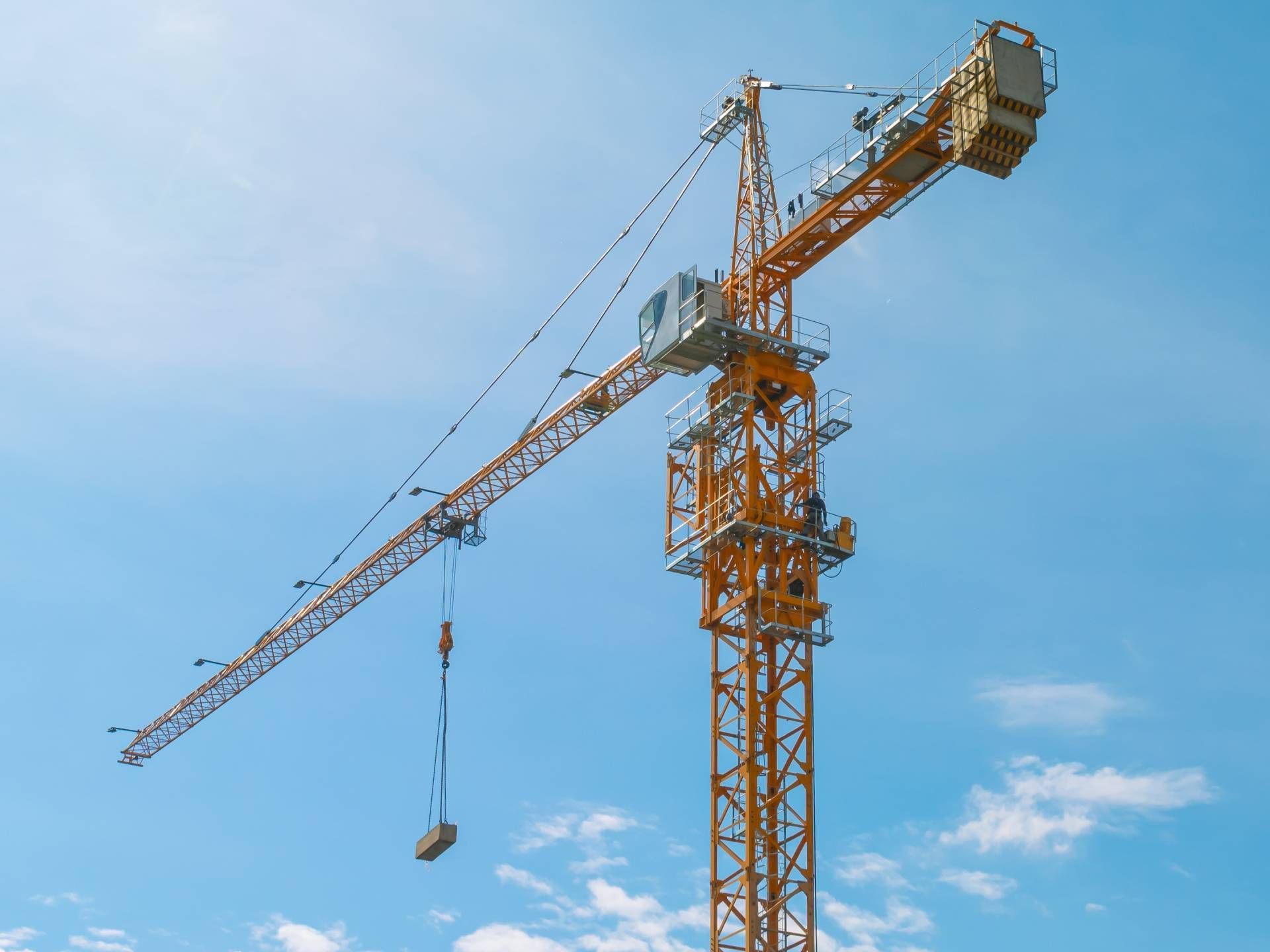 A large yellow construction crane is against a blue sky.