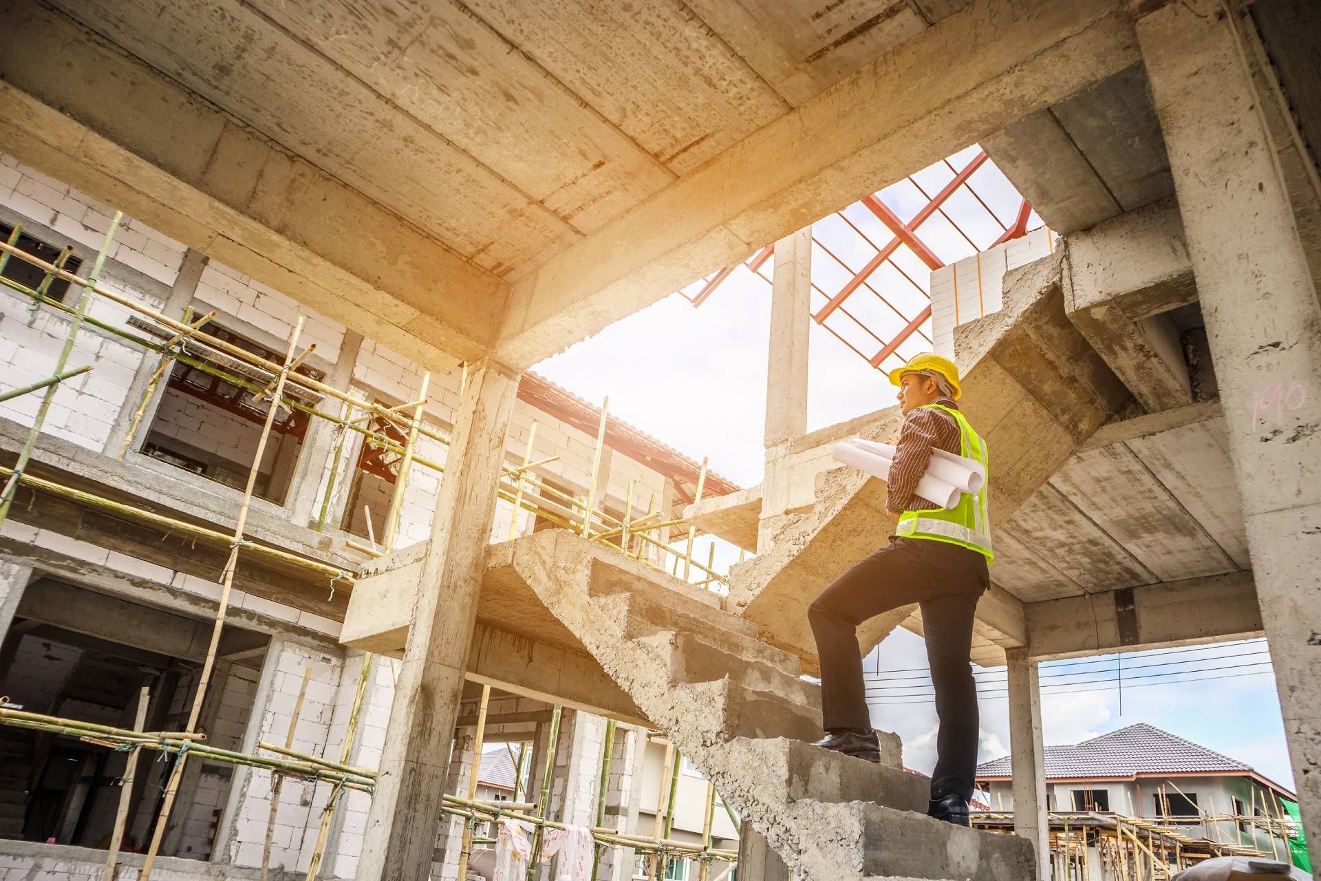A construction worker is standing on the stairs of a building under construction.