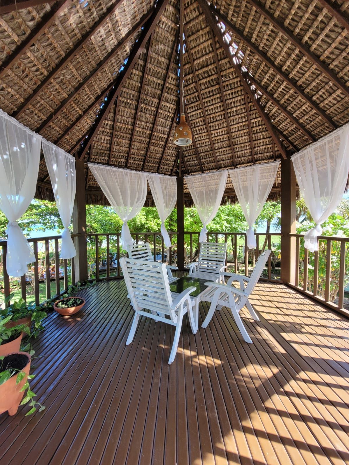 Um mirante com uma mesa e cadeiras sob um telhado de palha