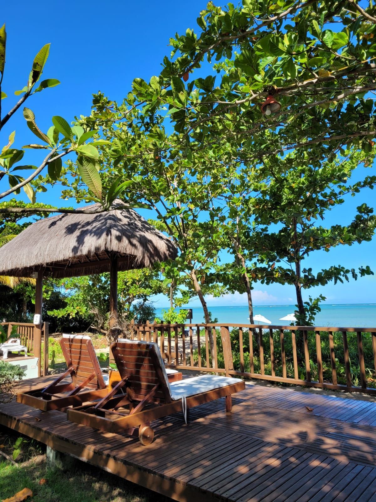 Um deck de madeira com cadeiras e um mirante com vista para o oceano