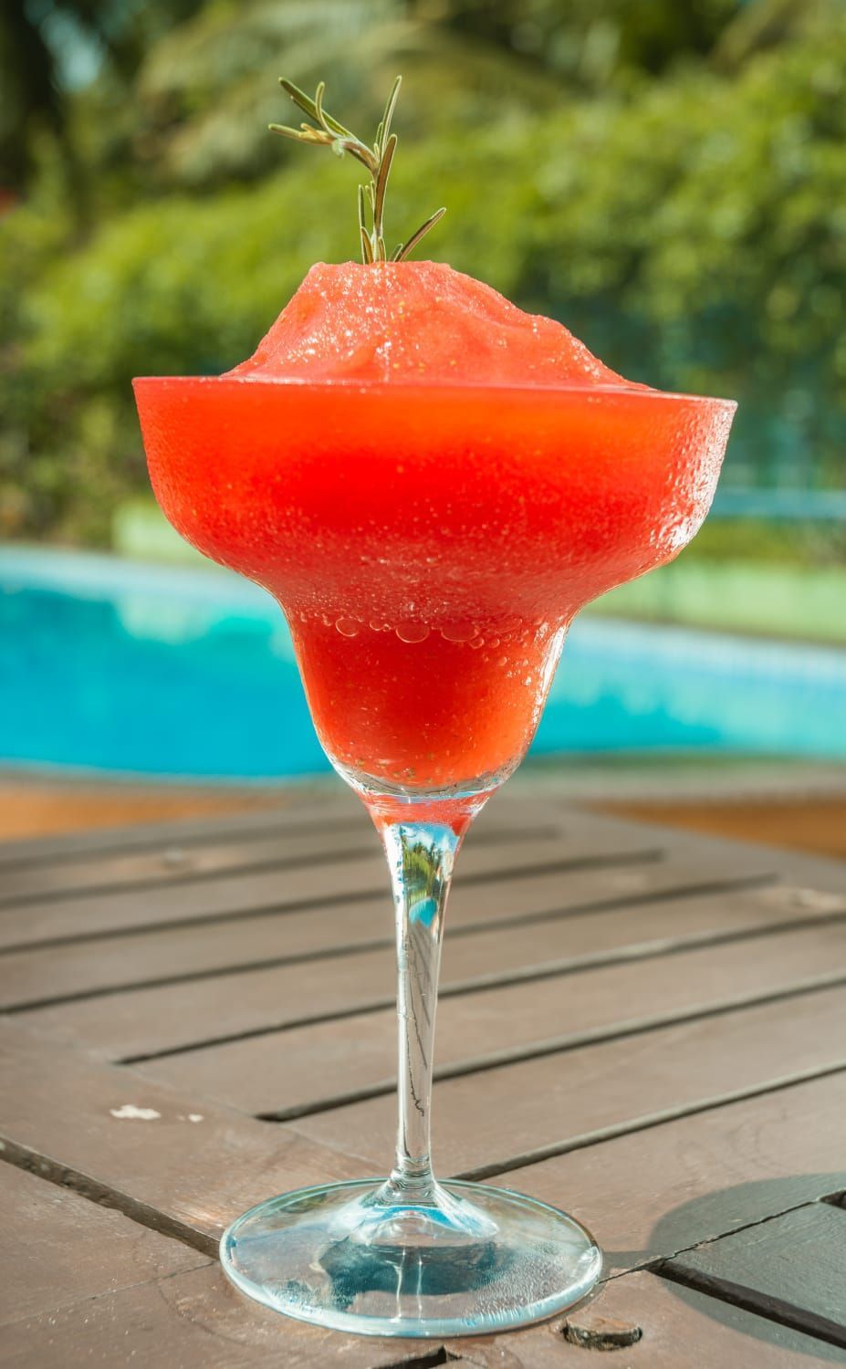 Uma margarita de melancia em uma taça de martini sobre uma mesa de madeira.