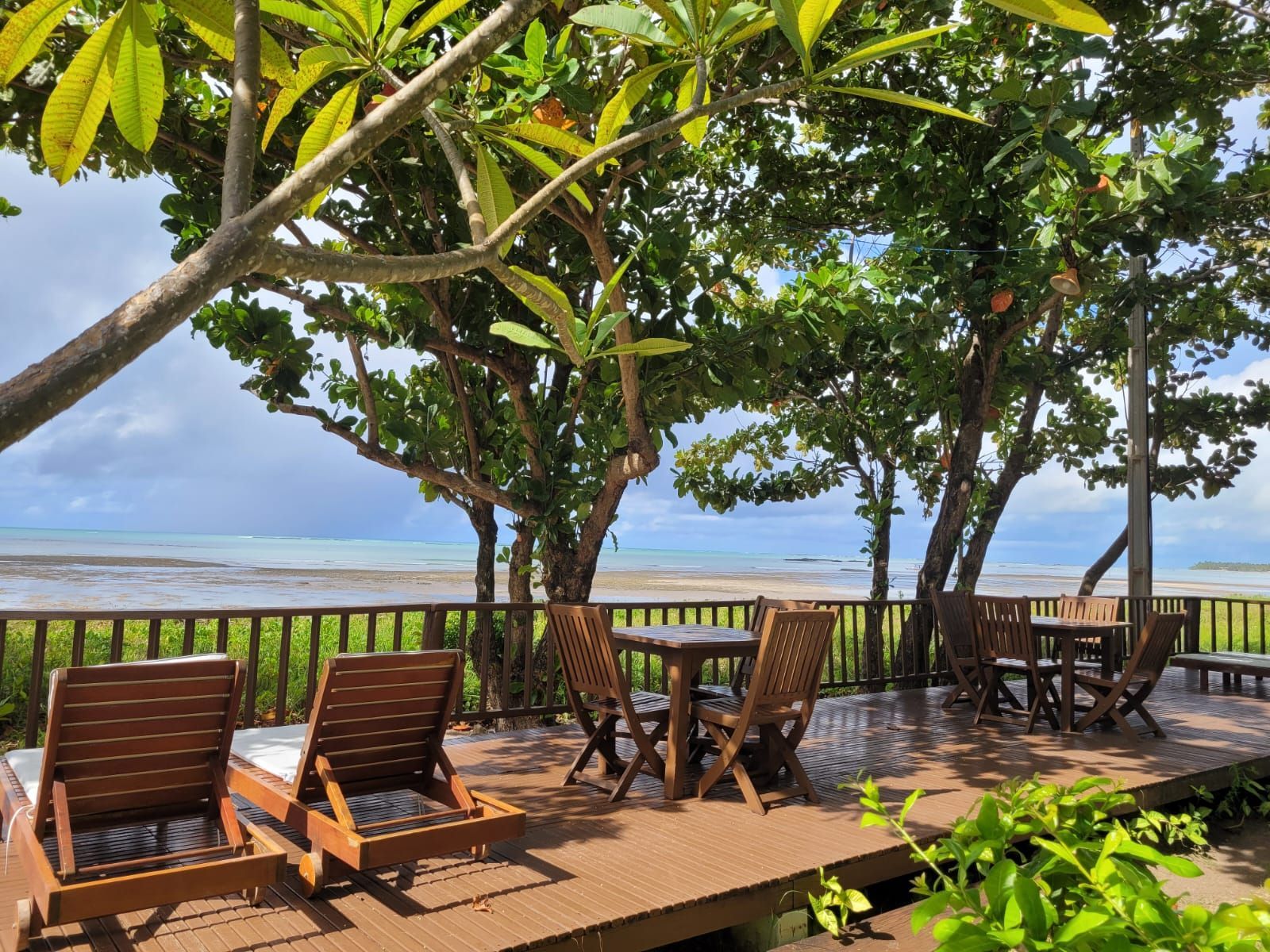 Um deck de madeira com cadeiras e mesas com vista para o oceano