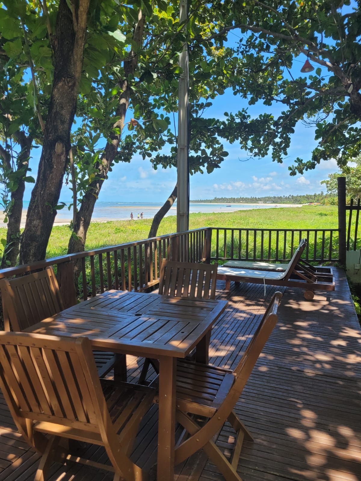 Uma mesa de madeira e cadeiras em um deck com vista para o oceano