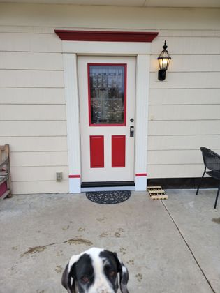 A person in overalls installs a brown door in a white room.