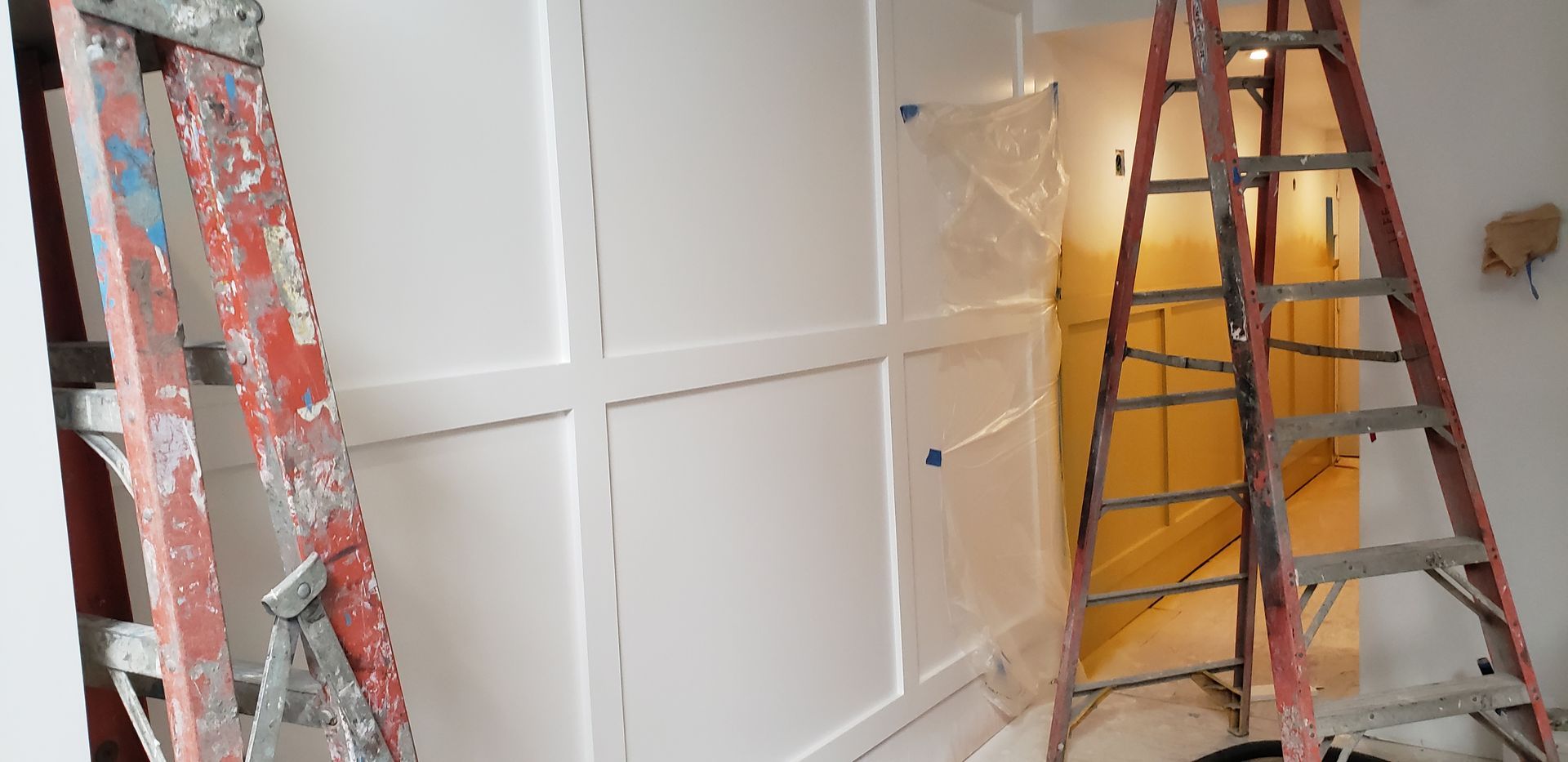 Hands in white gloves working with a wood-grain panel on a blue machine.