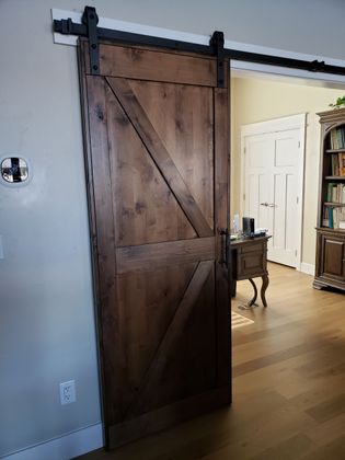 Brown wooden front door with sidelight, slate steps, and potted plants.