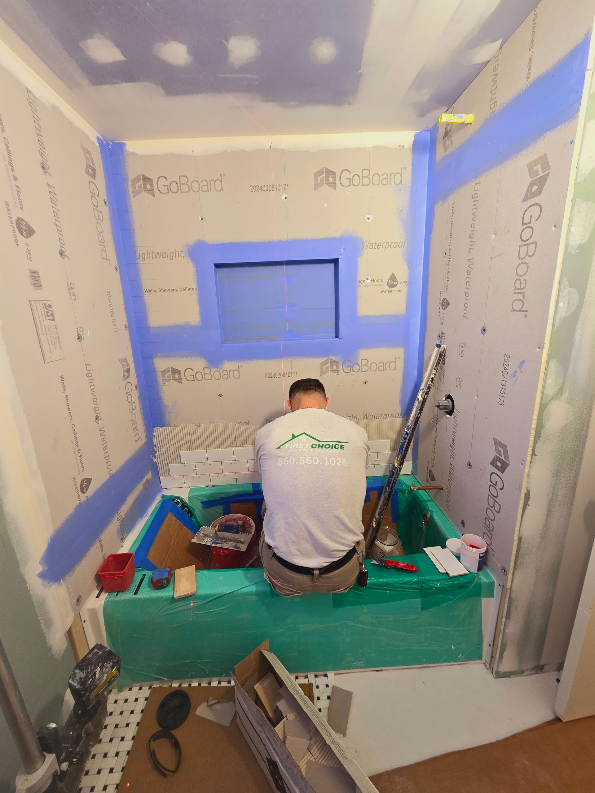 A man is kneeling in a bathtub in a bathroom under construction