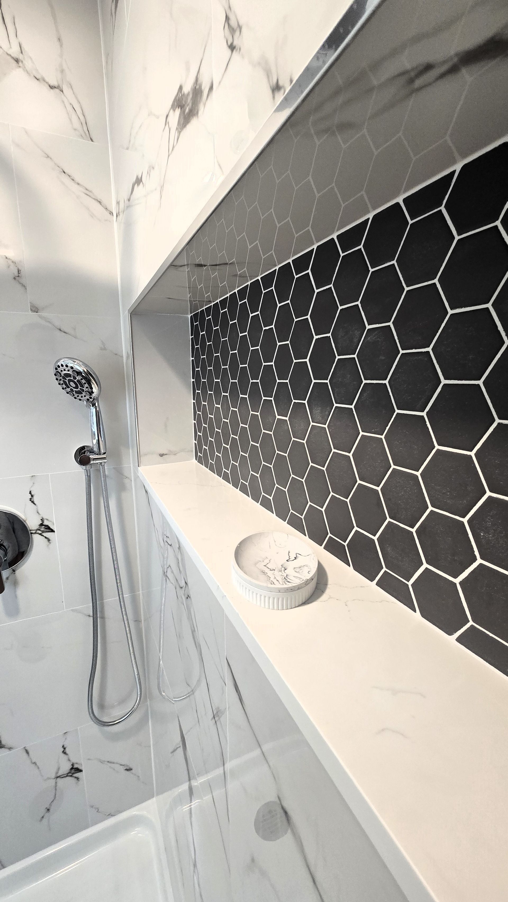 A bathroom with black and white tiles and a shower head.