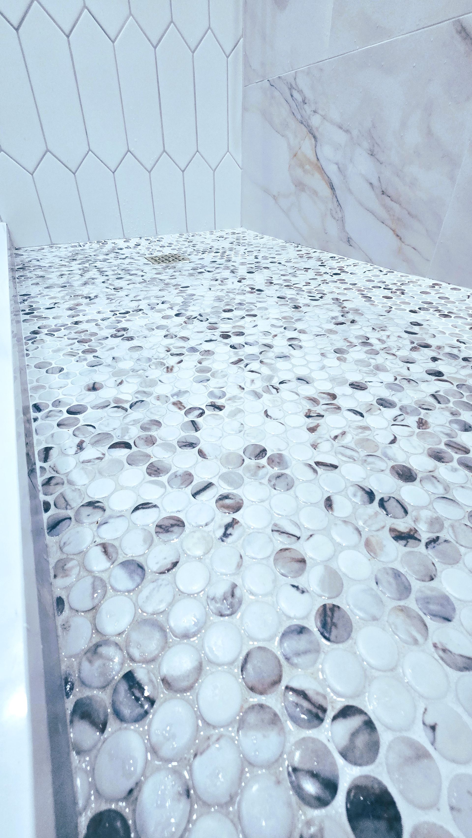 A bathroom with a walk in shower mosaic tiles on the shower floor.