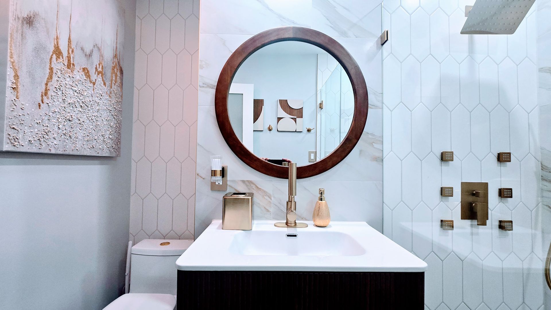 Modern bathroom remodel in East Hartford, CT with white and gold accents, including a sink, mirror, and shower.