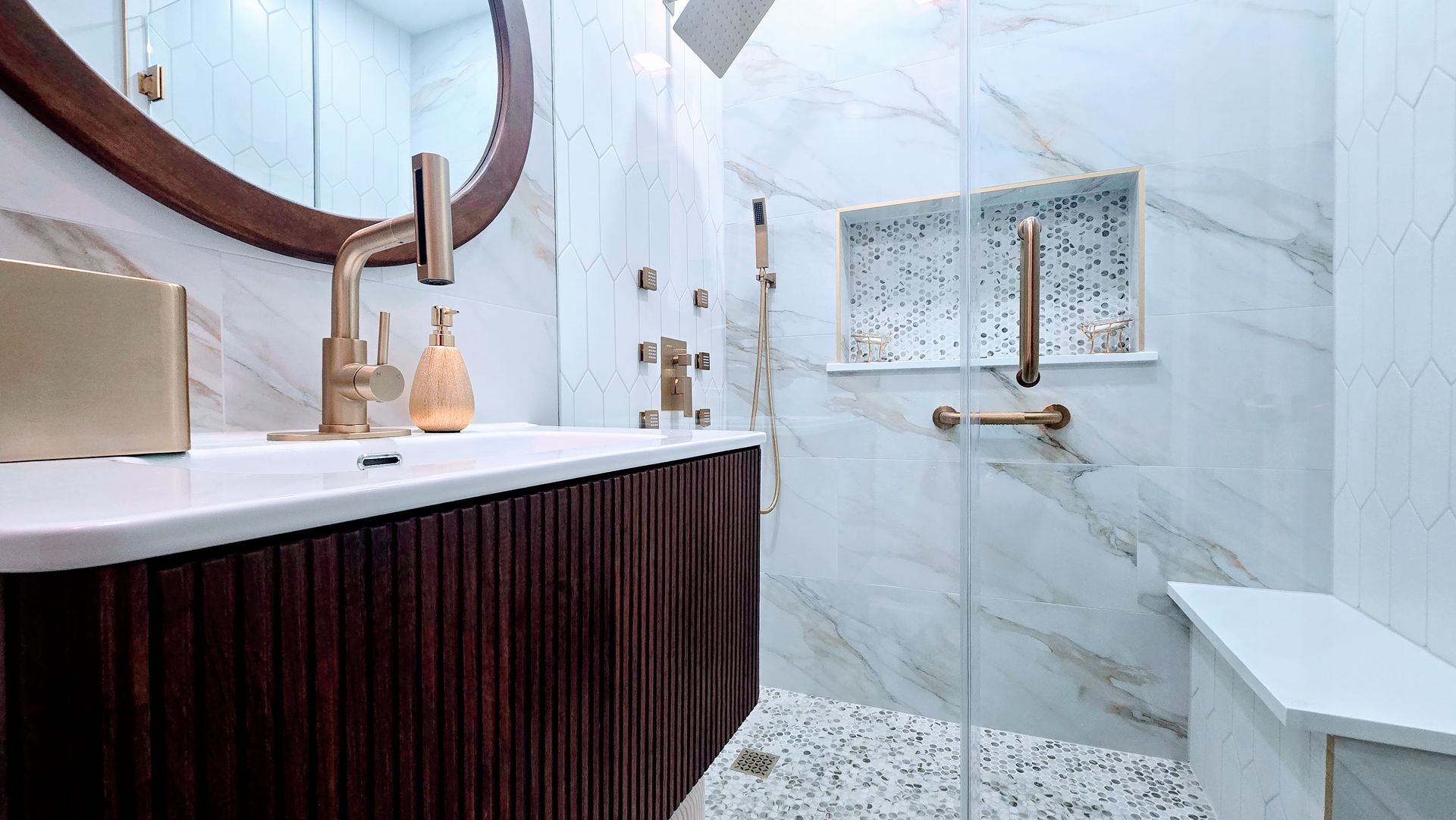 Elegant bathroom renovation in Wolcott, CT with a dark green vanity, white tub, gold accents, and a large arched mirror.