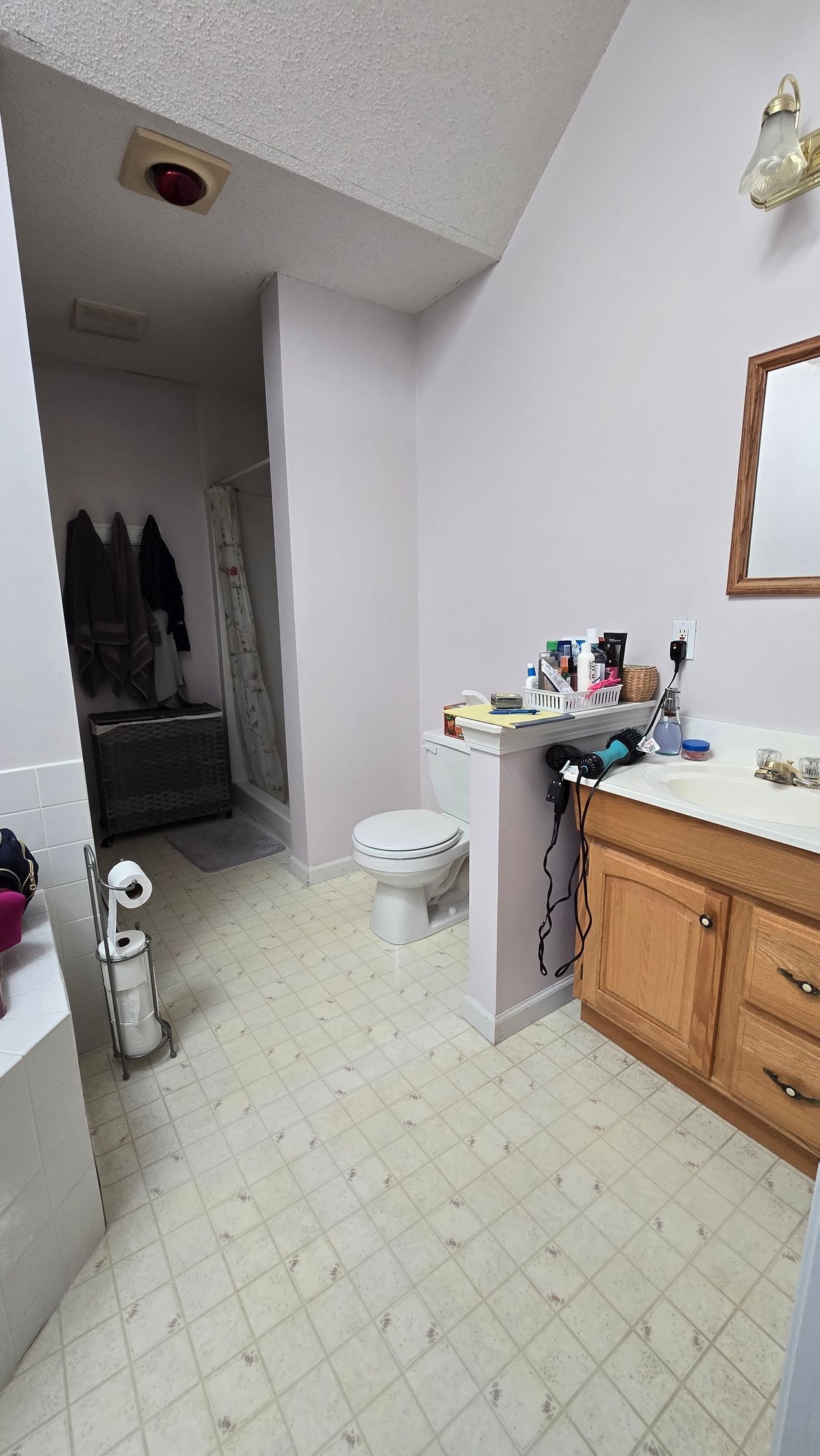 A bathroom with a toilet , sink and mirror.