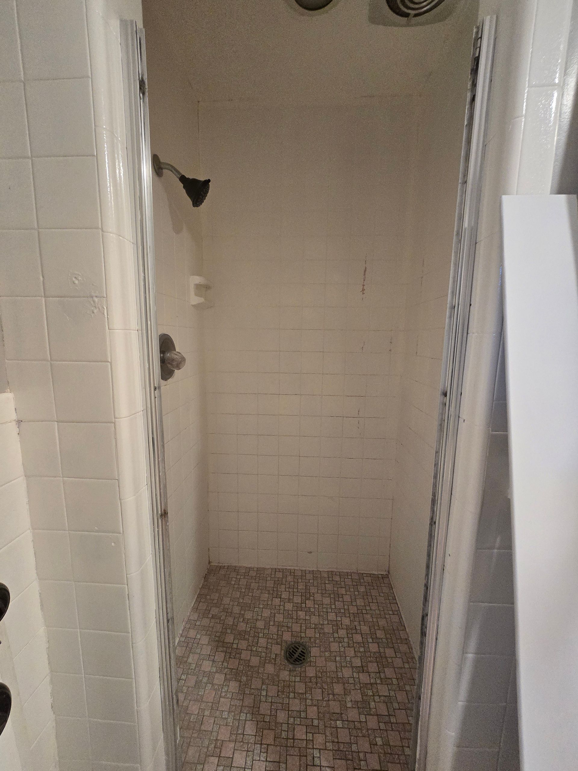 A shower with a built in shelf and a shower head